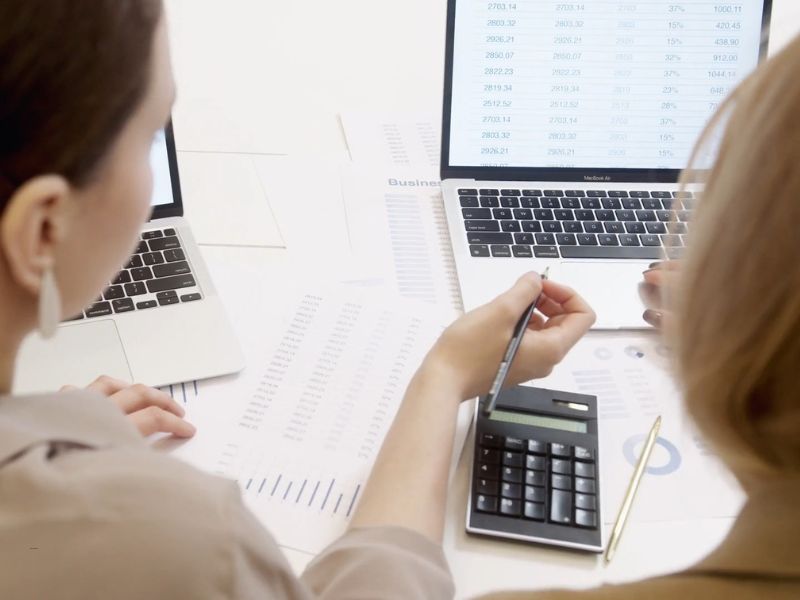 dve devojke, knjigovođe, rade za kompjuterom i papirima