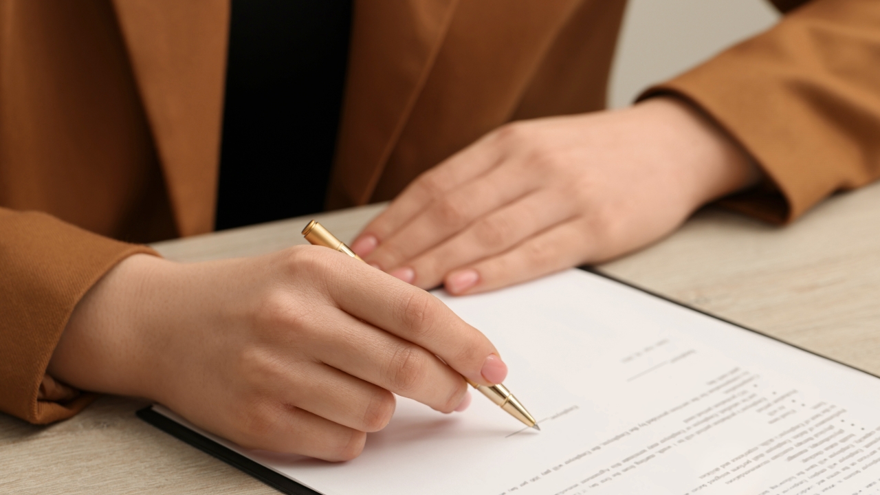 Osoba potpisuje dokument olovkom kao simbol izbora između ugovora o delu i paušala
