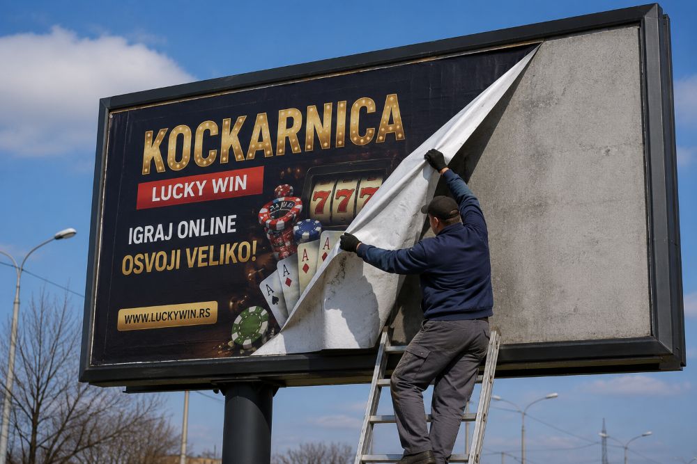 Radnik na merdevinama skida reklamu za kockarnicu sa velikog bilborda